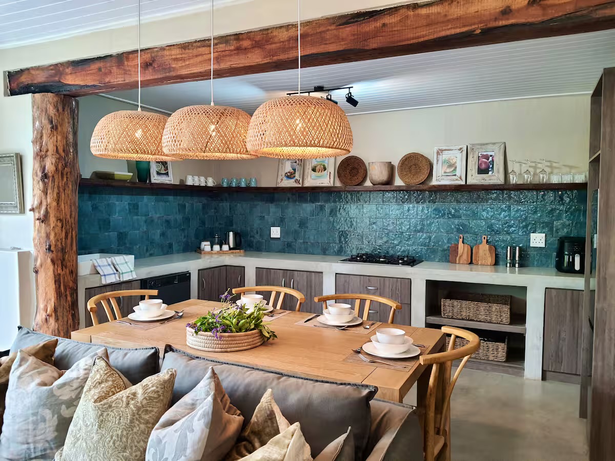 Open plan kitchen and dining with teal splashback and woven pendants